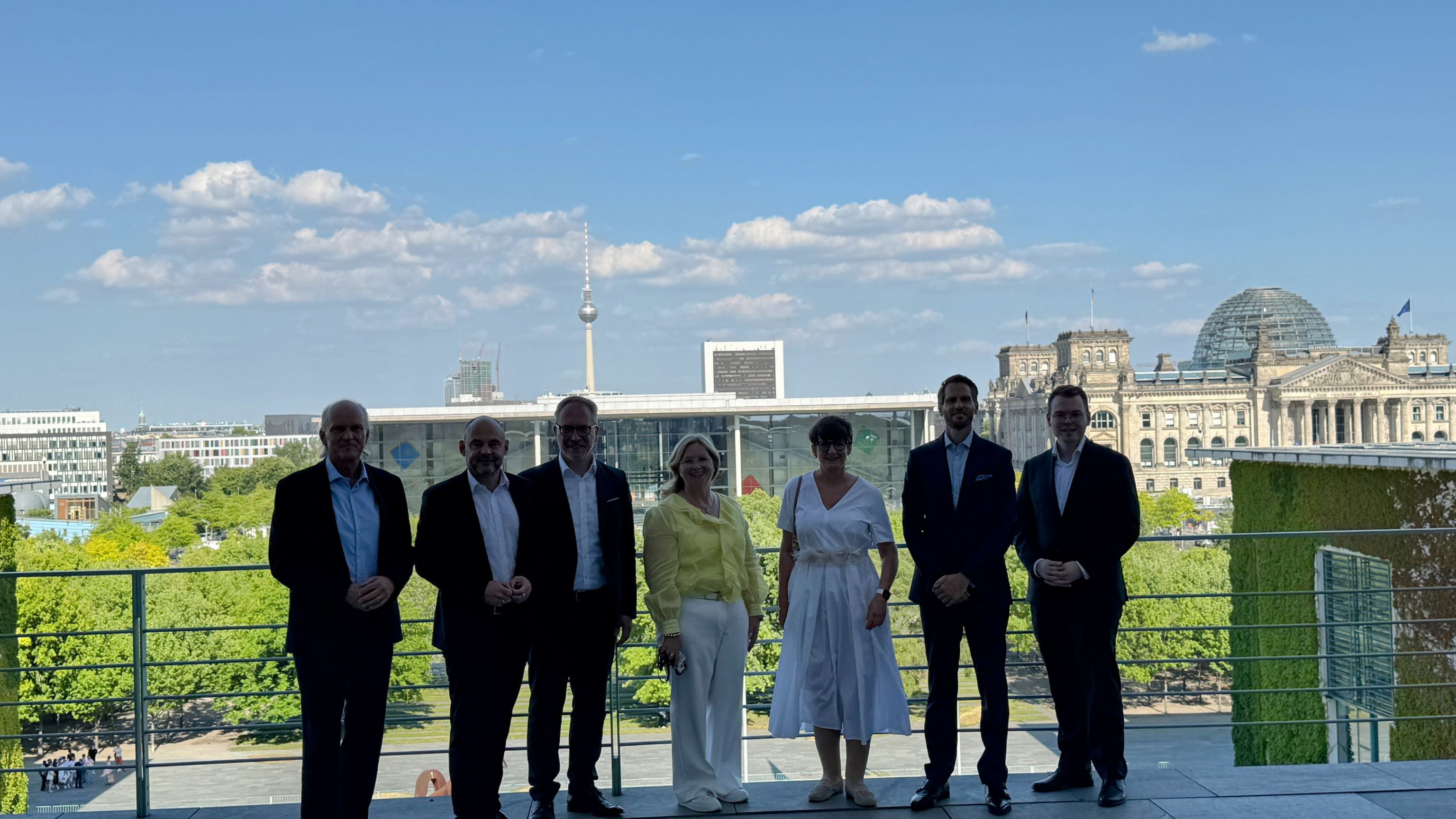 Gruppe von sechs Personen vor Berliner Reichstagsgebäude bei Sonnenschein.