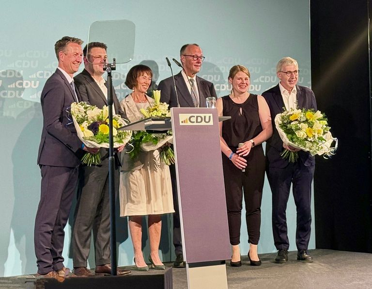 Fünf Personen auf Bühne mit Blumensträußen bei CDU-Veranstaltung, feierlicher Anlass.