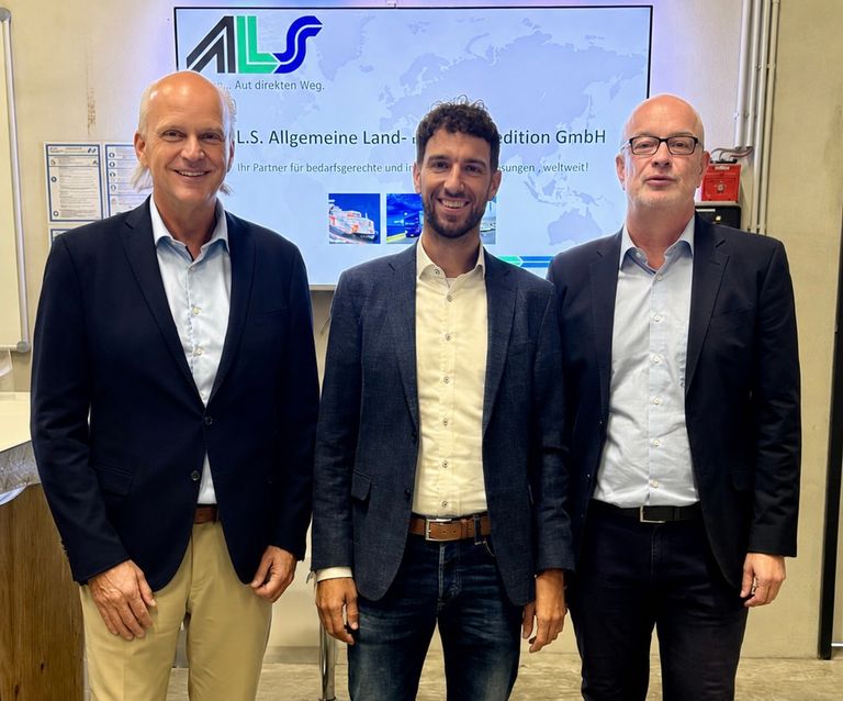 Drei Geschäftsleute vor Schild der ALS Allgemeine Land- und Stadtentwicklungs GmbH.