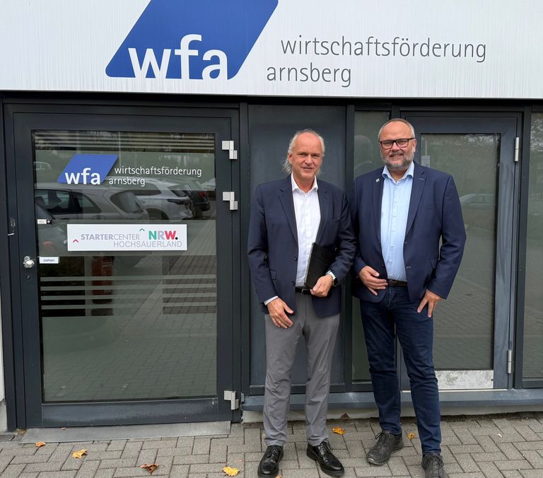 Zwei Herren vor WFA Wirtschaftsförderung Arnsberg Bürotür stehend, professionell lächelnd.
